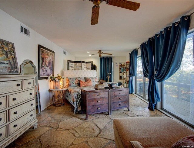 bedroom with access to exterior, visible vents, stone tile floors, and a ceiling fan