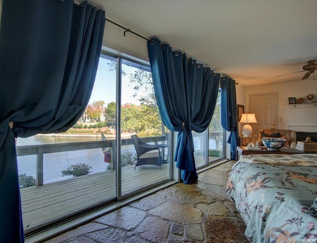 bedroom featuring access to exterior, stone tile flooring, and a water view