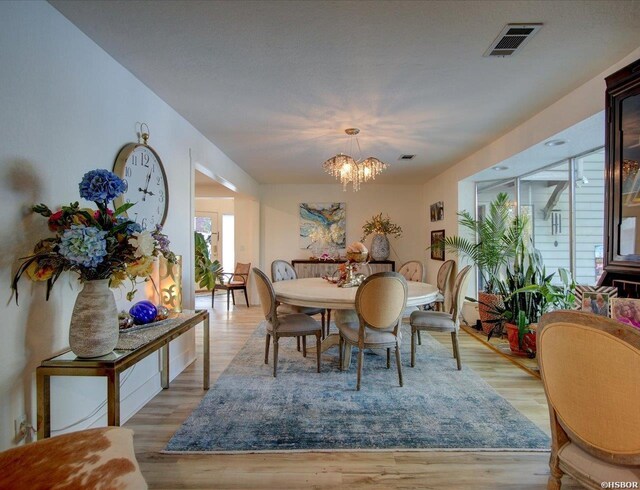 dining area featuring an inviting chandelier, light wood-style flooring, and visible vents