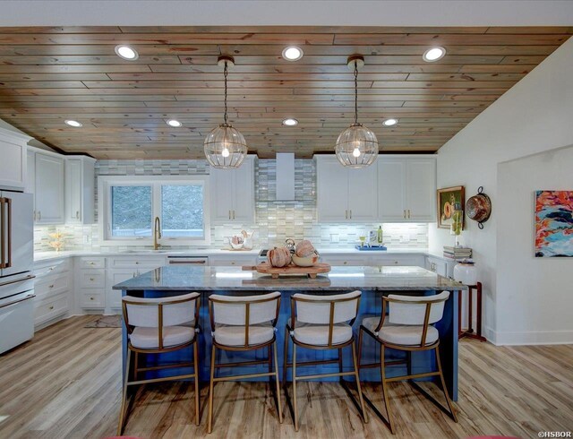 kitchen with light stone counters, a center island, pendant lighting, and white cabinets