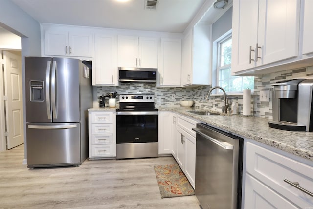 kitchen featuring visible vents, a sink, backsplash, stainless steel appliances, and white cabinets