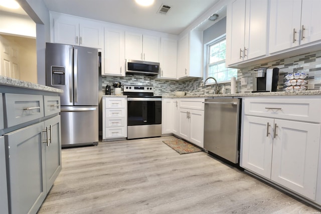 kitchen with visible vents, light stone countertops, appliances with stainless steel finishes, and light wood-style flooring