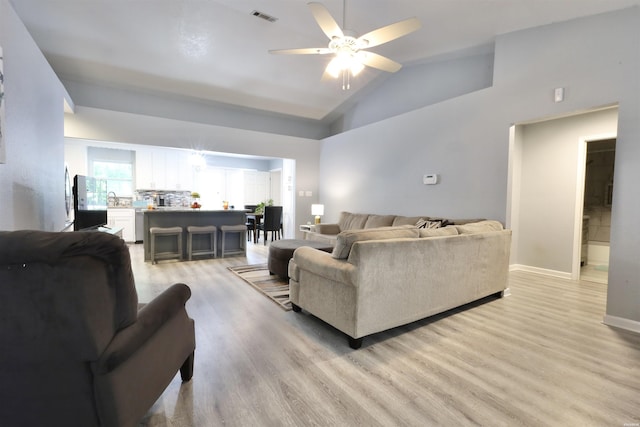 living area with visible vents, high vaulted ceiling, light wood finished floors, baseboards, and ceiling fan