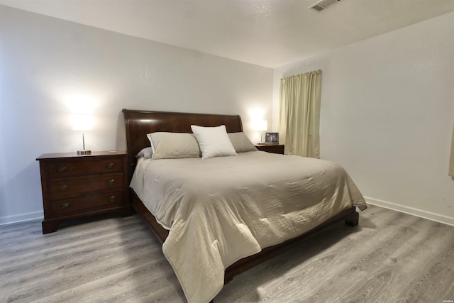 bedroom featuring visible vents, baseboards, and light wood-style floors