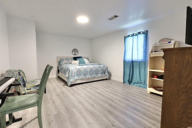 bedroom with wood finished floors, visible vents, and baseboards