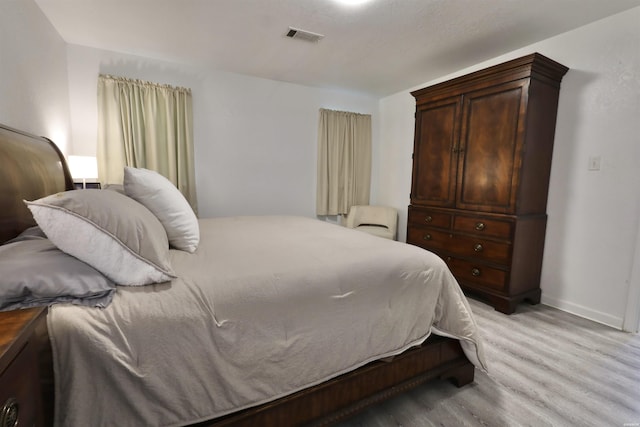 bedroom featuring baseboards, visible vents, and light wood finished floors