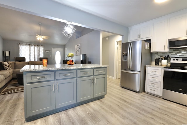 kitchen featuring backsplash, open floor plan, appliances with stainless steel finishes, white cabinets, and light wood finished floors