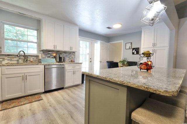 kitchen with visible vents, a sink, decorative backsplash, white cabinets, and stainless steel dishwasher