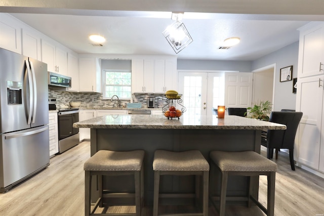 kitchen with tasteful backsplash, visible vents, a kitchen breakfast bar, french doors, and stainless steel appliances