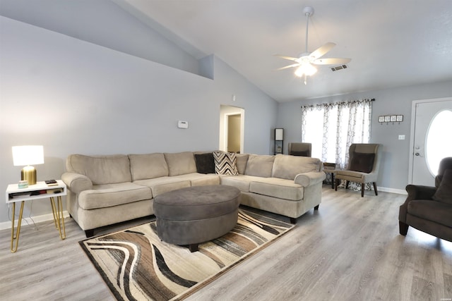 living area with visible vents, baseboards, light wood-style floors, and vaulted ceiling