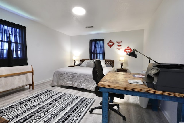 bedroom with visible vents, baseboards, and wood finished floors