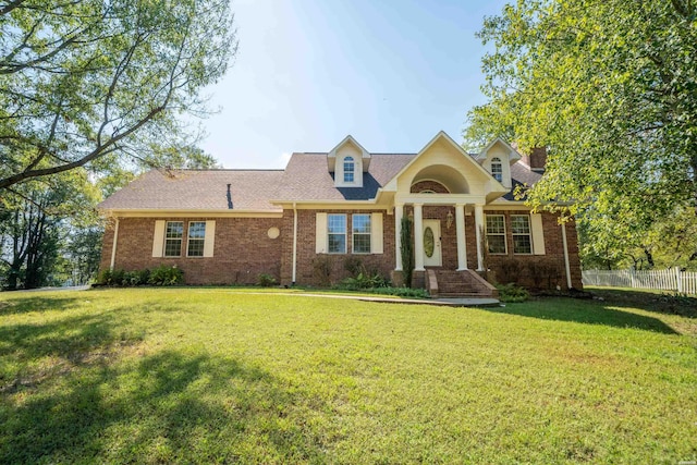 view of front of home with roof with shingles, fence, a front lawn, and brick siding