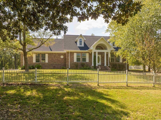 cape cod home featuring a fenced front yard, a front lawn, and brick siding