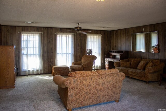 living room with carpet floors, ceiling fan, a textured ceiling, and wooden walls