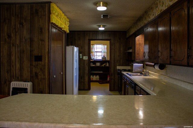 kitchen with dishwasher, freestanding refrigerator, light countertops, dark brown cabinets, and a sink