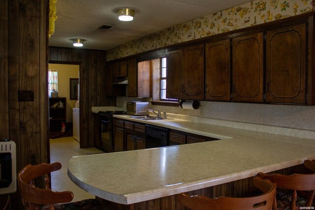 kitchen with black appliances, dark brown cabinets, a peninsula, and light countertops