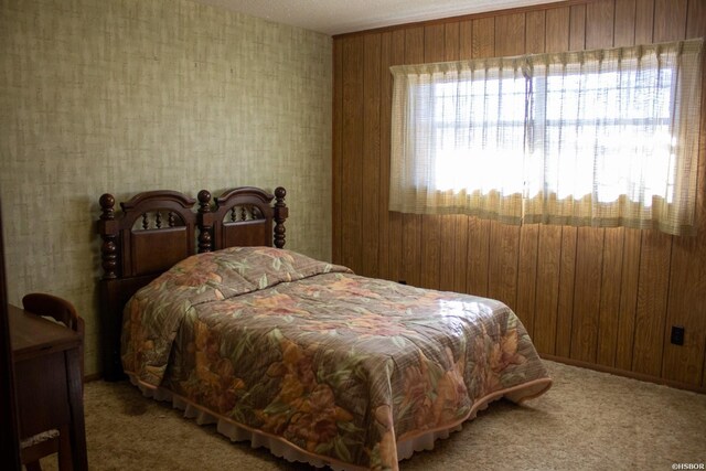 carpeted bedroom featuring wood walls