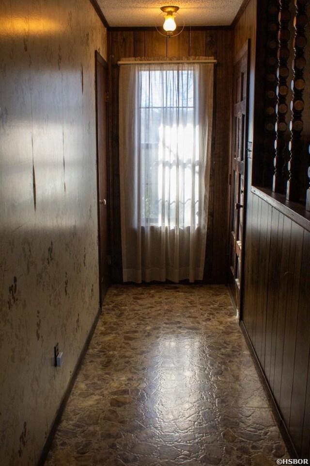 entryway with a textured ceiling, crown molding, and wooden walls