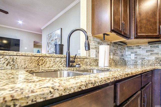 details with ornamental molding, a sink, backsplash, and light stone countertops