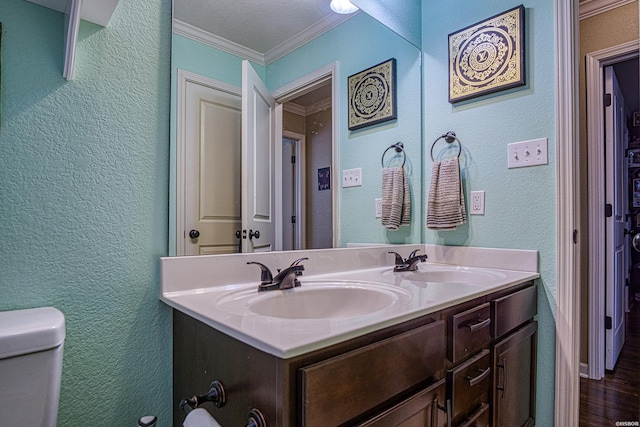 bathroom with double vanity, crown molding, a sink, and a textured wall