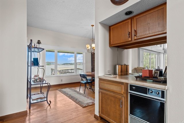 105 Long Island Bay Unit A1, Hot Springs, AR 71913 - kitchen featuring wood finished floors, brown cabinetry, a chandelier, and decorative light fixtures