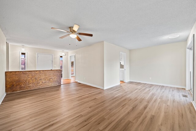 unfurnished living room featuring ceiling fan, a textured ceiling, visible vents, baseboards, and light wood finished floors