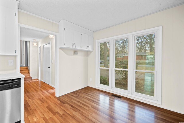 kitchen with light countertops, visible vents, stainless steel dishwasher, white cabinets, and light wood-type flooring