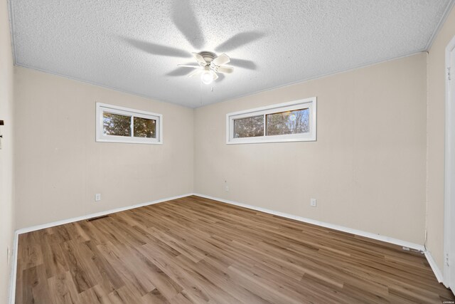 spare room with a ceiling fan, a textured ceiling, baseboards, and wood finished floors