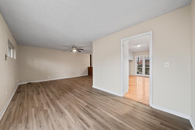 spare room with baseboards, ceiling fan, light wood-style flooring, and a textured ceiling