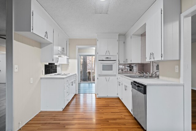 kitchen featuring white appliances, light countertops, a sink, and white cabinetry