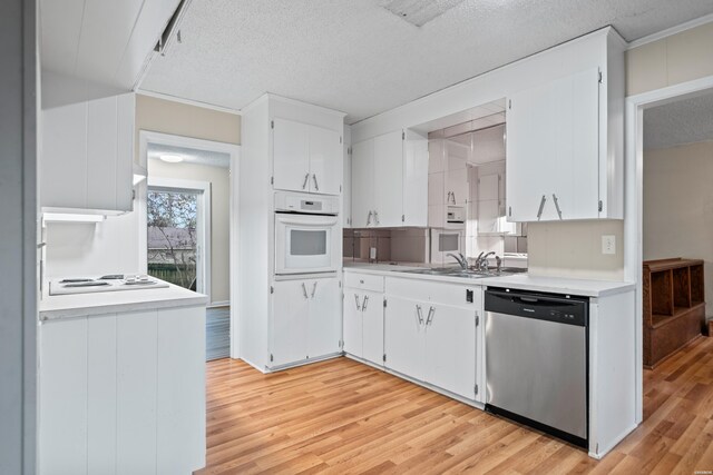 kitchen featuring white appliances, light countertops, a sink, and white cabinetry