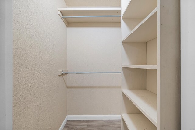 walk in closet with wood finished floors