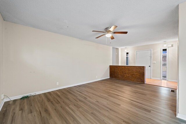 spare room featuring visible vents, ceiling fan, a textured ceiling, wood finished floors, and baseboards