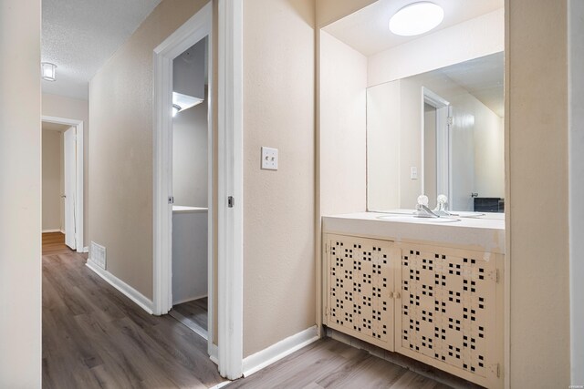 bathroom with visible vents, a textured ceiling, vanity, wood finished floors, and baseboards