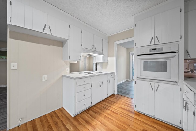 kitchen featuring light countertops, white oven, light wood-style flooring, and white cabinetry