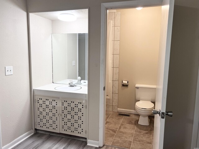 bathroom featuring toilet, vanity, visible vents, and baseboards