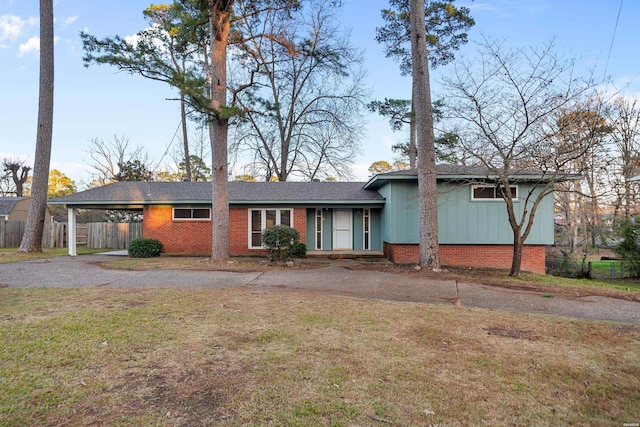 view of front of home featuring driveway, an attached carport, a front lawn, board and batten siding, and brick siding