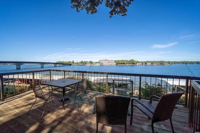 wooden terrace with a water view and outdoor dining area