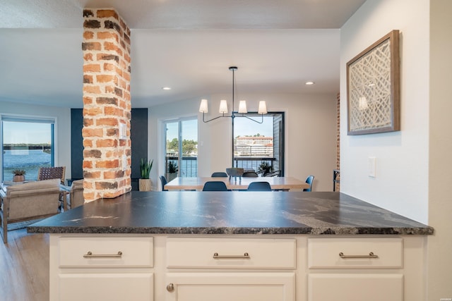 kitchen featuring open floor plan, a chandelier, white cabinetry, and pendant lighting