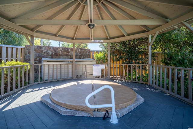 wooden deck with a covered hot tub and a gazebo