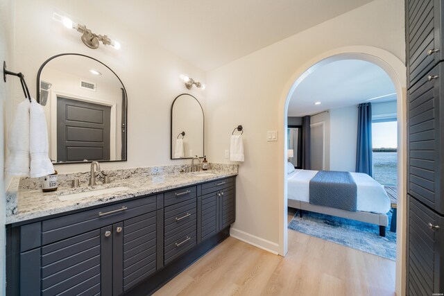 full bathroom featuring a water view, visible vents, ensuite bathroom, a sink, and wood finished floors