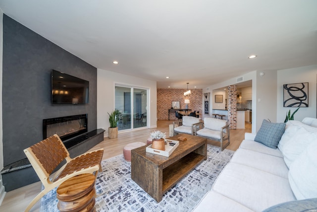 living area featuring recessed lighting, an accent wall, visible vents, light wood-type flooring, and a glass covered fireplace