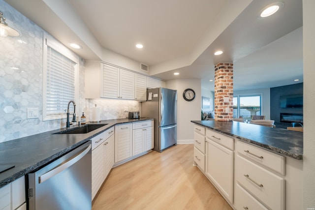 kitchen with tasteful backsplash, stainless steel appliances, light wood-style floors, white cabinetry, and a sink