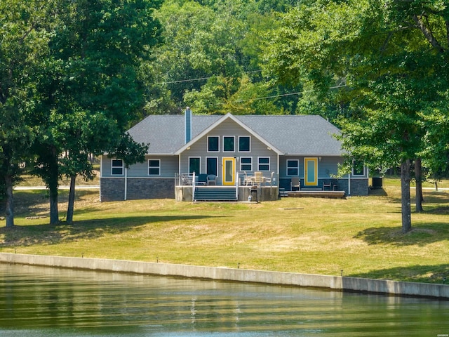 view of front of property with a front yard, stone siding, and a deck with water view