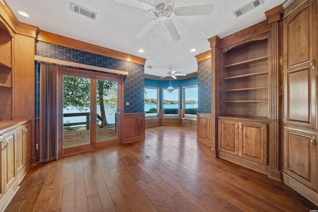69 Resplandor Way, Hot Springs Village, AR 71909 - unfurnished dining area with a textured ceiling, visible vents, ceiling fan, crown molding, and dark wood-type flooring