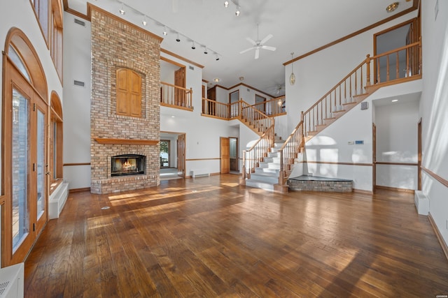 69 Resplandor Way, Hot Springs Village, AR 71909 - unfurnished living room featuring a towering ceiling, french doors, a fireplace, hardwood / wood-style flooring, and ceiling fan