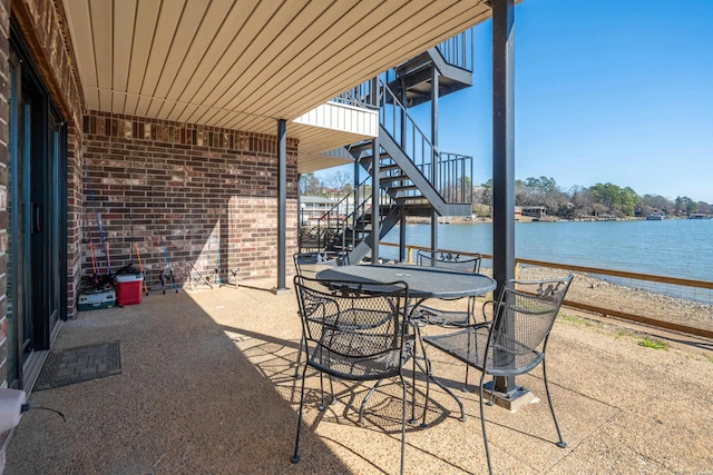 view of patio / terrace featuring stairs, outdoor dining area, and a water view