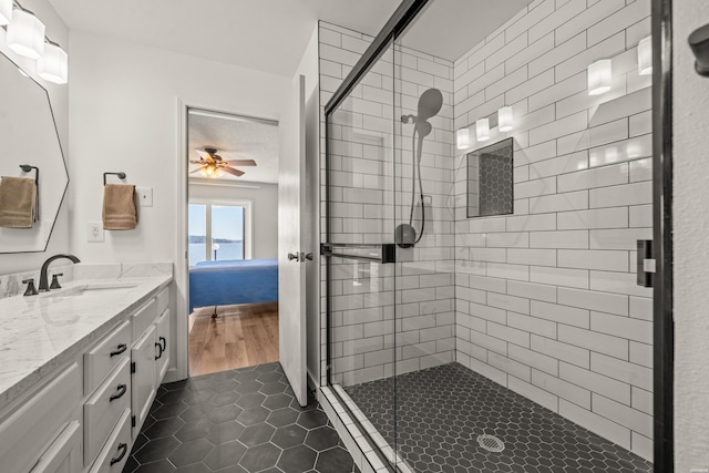 ensuite bathroom featuring tile patterned floors, a shower stall, a ceiling fan, and vanity