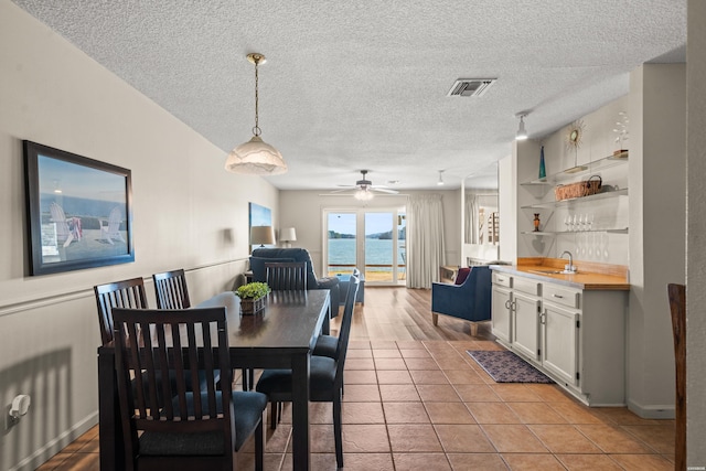 dining space with built in features, light tile patterned floors, visible vents, a textured ceiling, and baseboards