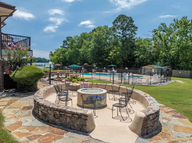 view of patio / terrace featuring an outdoor fire pit, fence, and a community pool